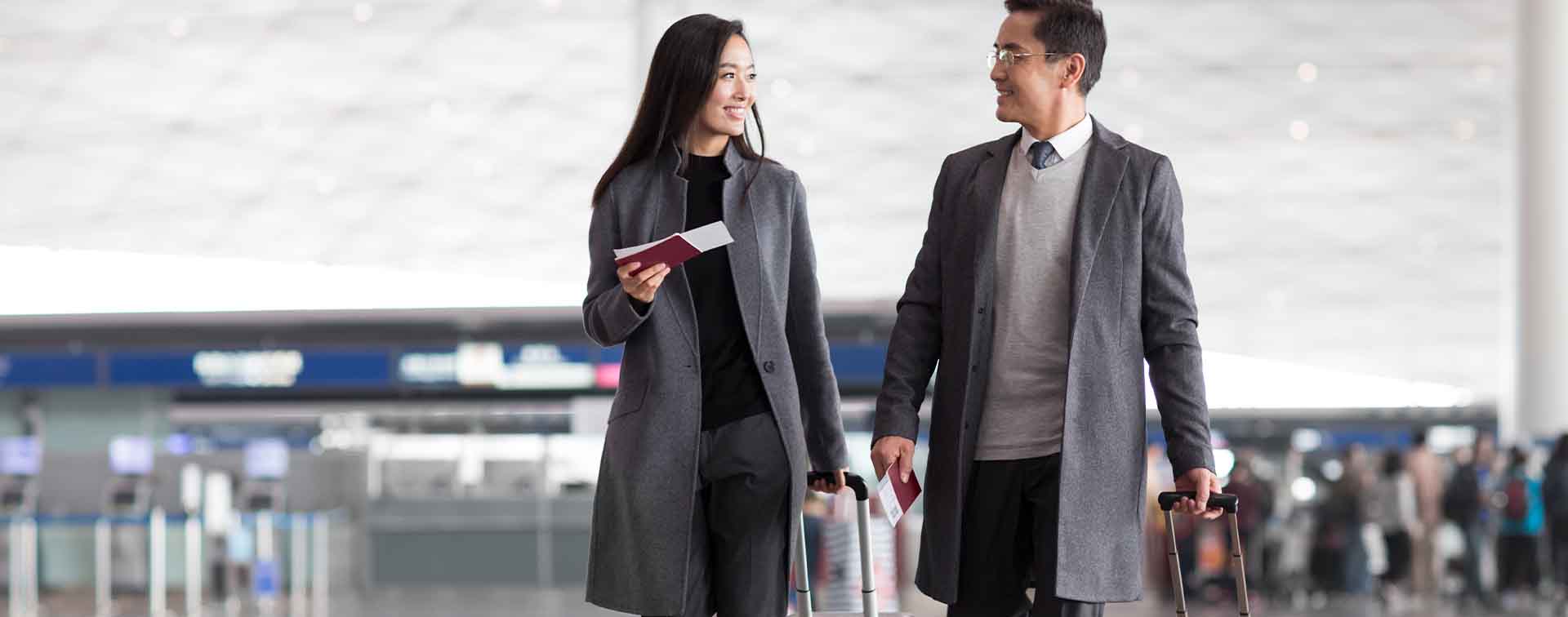 Businesspeople with passports in hand pulling suitcases in an airport lobby