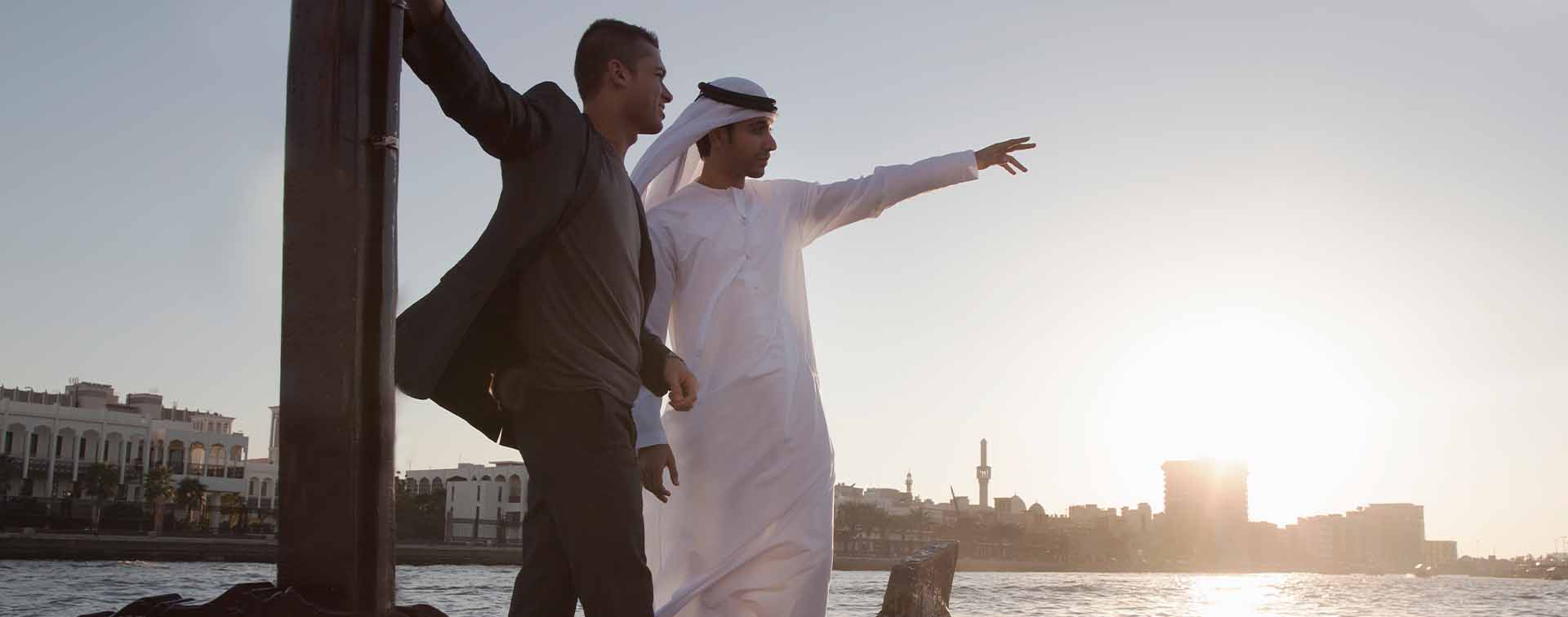 Two men looking out with the one pointing at something out in the distance.