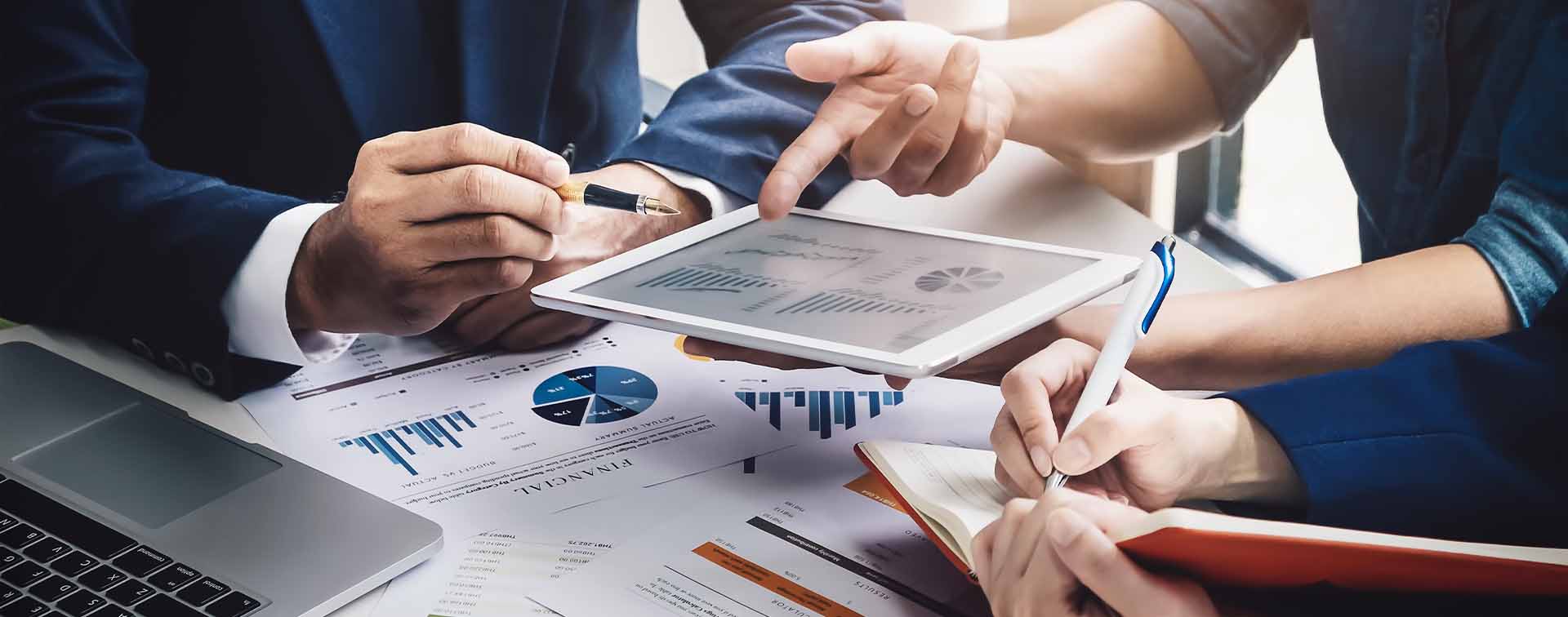 Wealth advisor consulting with client using tablet while assistant takes notes