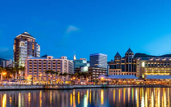 Illuminated waterfront promenade with restaurants and bars reflecting in the water of Port Louis, capital of Mauritius