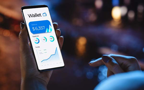 Woman using smartphone for checking balance of online wallet while standing on a neon-lit city street