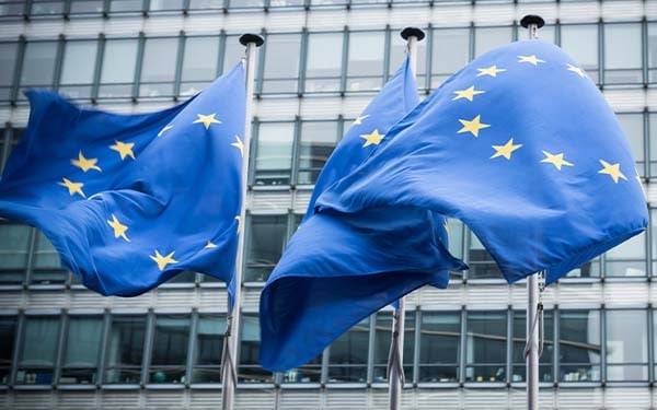 Three waving UN flags in front of an office building.