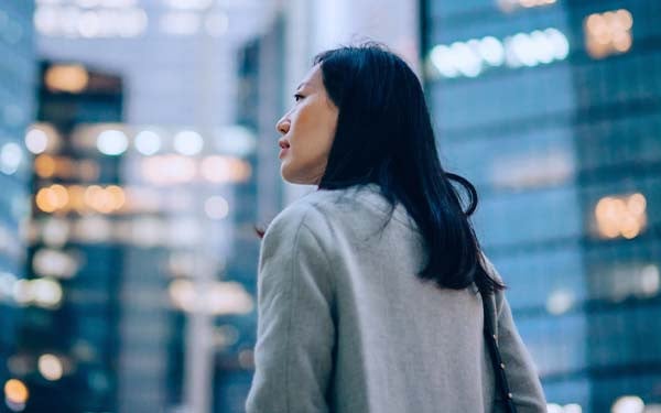 Side profile of a young Asian businesswoman standing among contemporary skyscrapers