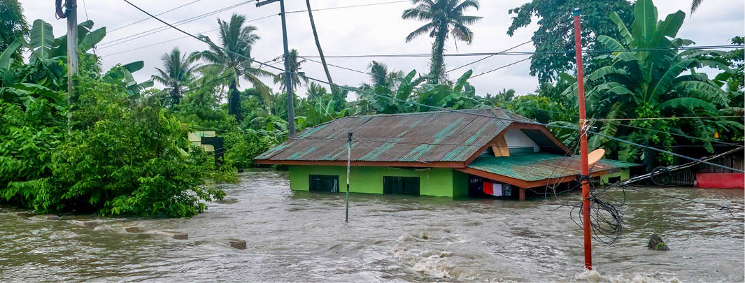 A rural house is nearly submerged by deep floodwater rushing off the National Highway between Baco and Calapan City in Oriental Mindoro province on July 23, 2021. The water level has been rising and now only the upper windows and rooftop are above the water. Conceptual for climate change issues.