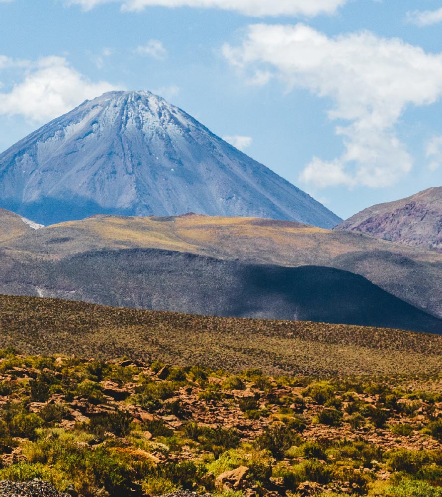 Volcanic peak with rugged terrain and blue sky.